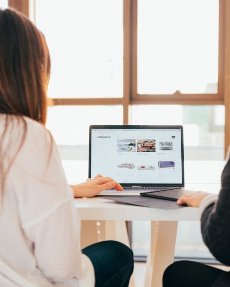 two women talking while looking at laptop computer