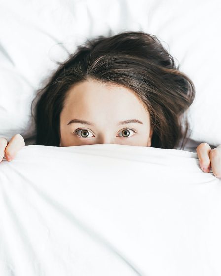 woman covering her face with blanket