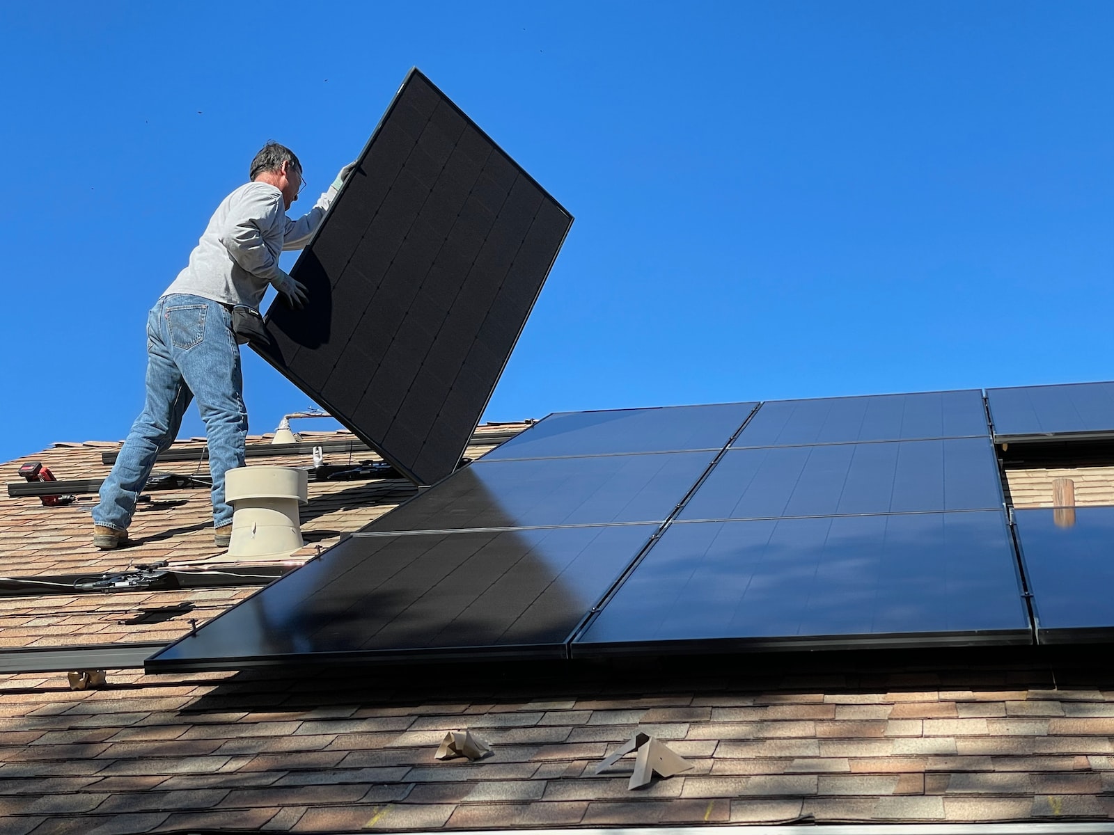 man in white dress shirt and blue denim jeans sitting on white and black solar panel