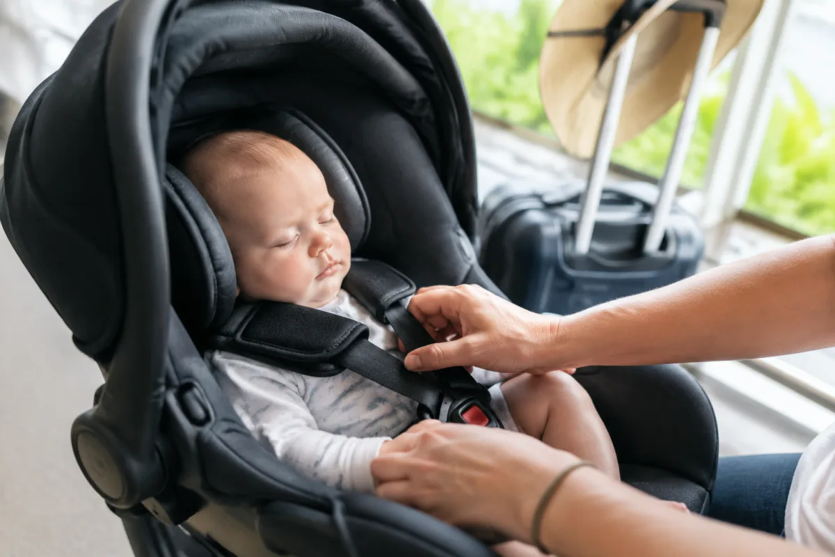 Crème solaire bébé et chapeau de paille posés sur une serviette en coton blanc