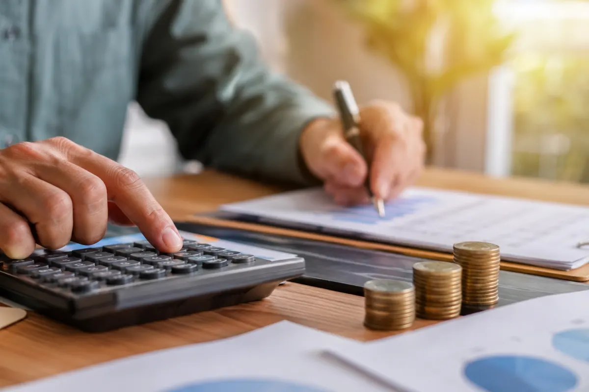 Gros plan sur une calculatrice une feuille de calcul et un stylo posés sur un bureau